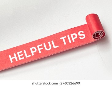 Helpful tips text on rolled red paper representing useful advice and practical guidance concept.