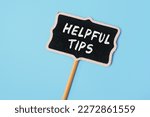 Helpful Tips - text on a small chalkboard on a blue background. Top view. Business, tips and tricks concept