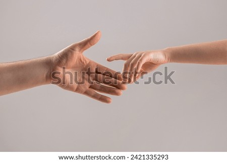 Helping hand concept, support. Help hand outstretched. Man and children hands reach toward each other. Child and father hands isolated on gray. Small child's hand reaches for the hand man.