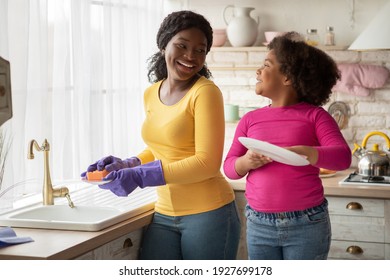 Helping Hand. Cute Little Black Girl Helps Mom In Kitchen, Happy African American Woman And Her Preschooler Daughter Washing And Wiping Dishes Together, Having Fun At Home, Free Space - Powered by Shutterstock