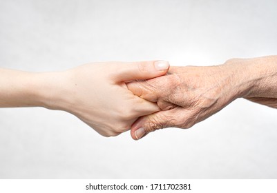 Helping hand for the elderly concept with young hand holding old hand. 