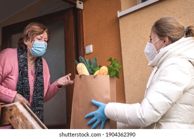 Helping Hand With Shopping Food During Pandemic Outbreak. Volunteer Wearing Ffp2 Mask During Delivering Groceries To Senior Woman. Support Local Elderly Community Due Covid-19 Lockdown