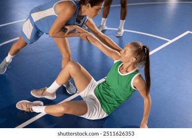 Helping teammate stand up, female basketball players on court during game. Teamwork, sportsmanship, support, competition, cooperation, athletic - Powered by Shutterstock