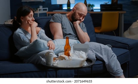 Helpless Unhappy, Depressed, Frustrated Young Couple Sitting In Couch Suffering From Insomnia, Stress Anxiety, Mental Problems, Suicidal Thoughts, Chronic Disease. People Looking Lost Into Space