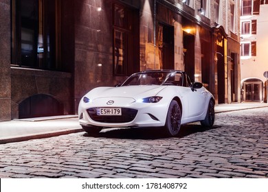 Helsinki, Finland 19 July 2020 Mazda MX-5 cabrio is the fourth and current generation of the Mazda MX-5. White Mazda Roadster stands on road with open roof in night time, background cityscape. 