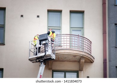 Helsinki, Finland - 22.08.2017: Two Window Cleaners (or Painters) Sanding And Painting And Wash The Balcony While In The Lift Basket