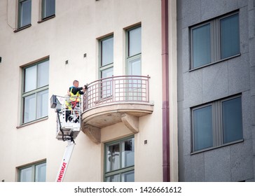 Helsinki, Finland - 22.08.2017: Two Window Cleaners (or Painters) Sanding And Painting And Wash The Balcony While In The Lift Basket