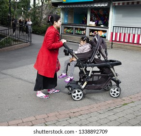 HELSINKI, FINLAND - AUGUST 22, 2017: Asian Woman With Baby Carriage Probably A Babysitter.