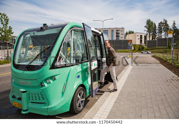 HELSINKI, FINLAND - JUNE 11, 2018: Automated\
remotely operated bus test in Helsinki. Unmanned public transport\
on street. Man on bus\
stop.
