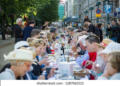 Helsinki, FINLAND - JUNE 12, 2018: Long Table With Lots Of People Eating And Drinking Together. The Day Of City Celebration In Centre Of Helsinki. Finnish Your Dinner Under The Sky.