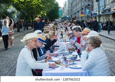 Helsinki, FINLAND - JUNE 12, 2018: Long Table With Lots Of People Eating And Drinking Together. The Day Of City Celebration In Centre Of Helsinki. Finnish Your Dinner Under The Sky.