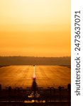 Helsinki, Finland - May 30st 2024: Airport marshaller vehicle on the runway centerline inspecting. Sunrise, golden sky and warm light, early morning. Helsinki-Vantaa International