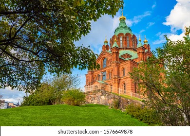 Helsinki. Finland. St. John's Church in Helsinki. Lutheran Church in Helsinki. Cathedral on the background of green trees and blue sky. Religious building. Brick Church with green roof.