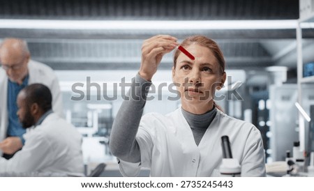 Hematology specialist in lab analyzing batch of blood samples for red blood cell abnormalities. Technician doing research on sanguine fluid vials to diagnose anemia types, camera B