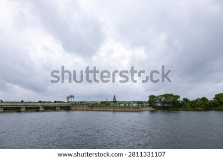 Hemavati Reservoir and dam under dramatic monsoon clouds in Hassan, Karnataka, India. Scenic waterscape ideal for travel, nature, engineering, environment, tourism, and editorial use.