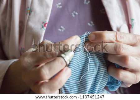 hemming a dress, woman hands needlework, detail of sewing hand