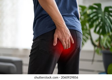 Hemorrhoidal pain, man suffering from hemorrhoids at home, painful area highlighted in red