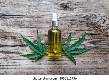 Hemp Cbd Oil Serum In Glass Dropper Bottle With Cannabis Leaves. Cannabis Leaf With Skincare Cosmetic Product CBD Oil On Old Wood Background.
