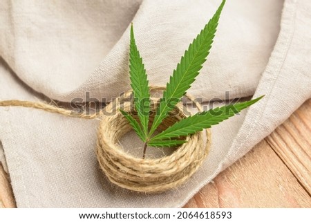 Hemp cloth with threads on wooden background, closeup