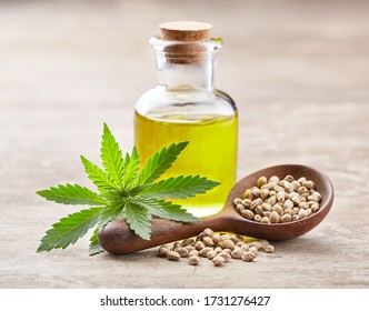 Hemp oil with seeds and cannabis plant on wooden board