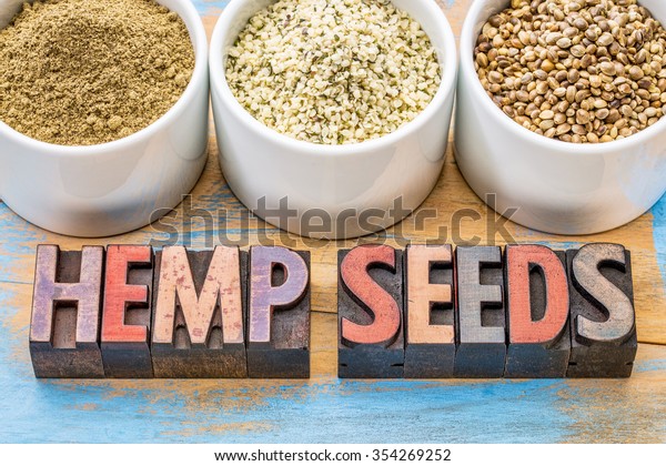 hemp products: seeds, hearts (shelled seeds) and protein powder in small ceramic bowls on a grunge wood with a text in vintage letterpress wood type
