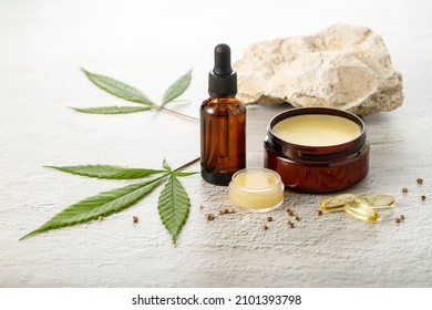 Hemp salve balm and relaxing CBD serum oil as a complex in the homeopathy  treatment of the musculoskeletal or calming nervous system or psoriasis with cannabis leaves and seeds on stone background - Shutterstock ID 2101393798