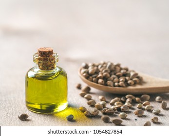 Hemp seeds and hemp oil on brown wooden table. Hemp seeds in wooden spoon and hemp essential oil in small glass bottle. Copy space for text