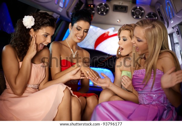 Hen party in limousine, girls looking at her\
friends engagement ring.?