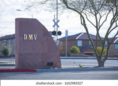 Henderson, NV 2/22/2020 — DMV sign on brick at the entrance to the Department of Motor Vehicles in the Las Vegas Valley area of Southern Nevada. Railroad crossing and homes in bokeh in background.