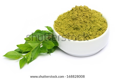 Henna leaves with powder on ceramic bowl over white background