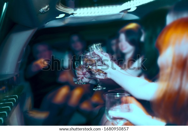 hen-party. girlfriend team night party.\
beautiful women clinking glasses inside limousine interior. focus\
on glasses. happy birthday party or exhaust.\
