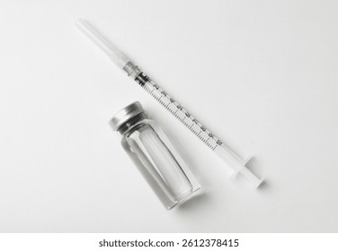 Hepatitis vaccine in glass vial and syringe on white background, top view