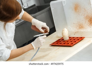 Her Decorating Secrets. Shot Of A Female Chef Decorating A White Chocolate Egg With An Air Brush 