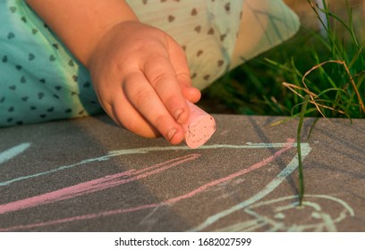 In her free time from school, the girl draws a pink chalk