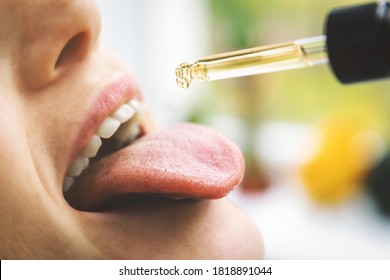 herbal alternative medicine and dietary supplements - woman taking cbd hemp oil drops in mouth from dropper. medical cannabis