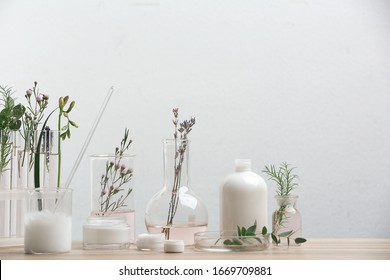 Herbal cosmetic products, laboratory glassware and ingredients on wooden table