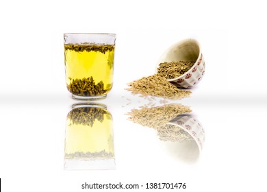 Herbal detoxifying drink isolated on white i.e. Jeera water with some raw organic cumin in a glass bowl.