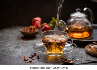 herbal flower tea from the petals of rose in a glass cup on dark gray background - Shutterstock ID 2070440948
