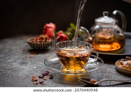 herbal flower tea from the petals of rose in a glass cup on dark gray background