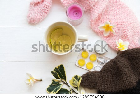 herbal honey lemon healthy drinks health care for sore throat ,lozenge with pink  knitting wool scarf of lifestyle woman relax in winter season and flowers frangipani decorate on background white