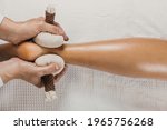 Herbal massage with pindas on the legs. Ayurveda medicine and aromatherapy treatment, anti-stress and anti-insomnia. Cotton cloth bags with herbs and medicinal plants.