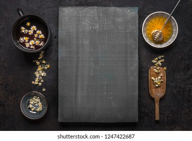  Herbal medicine background with loose dried chamomile flowers, cup of herbal tea and honey with spoon on wooden, top view . Healthy tea ingredients and  home remedy for cosmetic treatment. 
