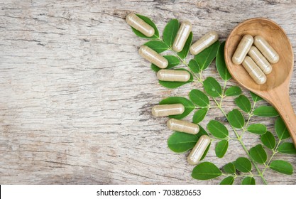 Herbal medicine in capsules from moringa leaf on rustic wooden table with copy space for medical background, healthy eating with natural product for good living 