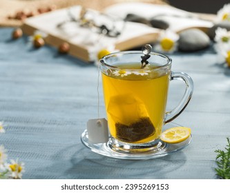 Herbal tea bag in a glass cup. Chamomile tea bag. Hot beverage concept in the desk