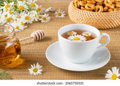 Herbal tea, chamomile flowers and honey on rattan matting Close-up