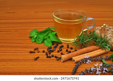 Herbal tea, medicinal immunity booster with ingredients ginger, cinnamon, Tulsi, basil leaves, black peppercorns, mint leaves, rosemary, cloves on a wooden table - Powered by Shutterstock