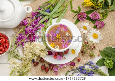 Herbal tea in a white cup on a white wooden table with flowers. Tea ceremony. Blooming Sally.