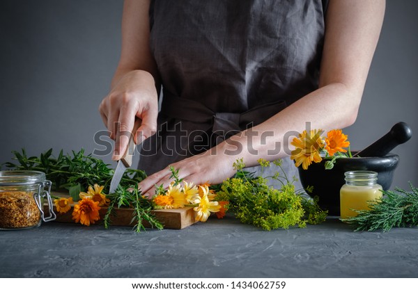 Herbalist woman chopping medicinal herbs with a\
knife to prepare healing medicines for treatment. Herbal medicine\
concept.