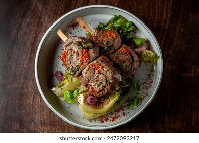 Herb-crusted beef chops on mixed greens, garnished with red spices. - Powered by Shutterstock