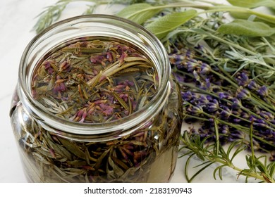 Herbs infused vinegar in open jar. Thieves vinegar, alternative medicine remedy with wormwood, sage, rosemary and lavender. Herbalism concept. - Shutterstock ID 2183190943